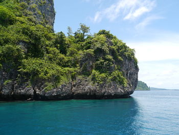 Scenic view of sea by mountain against sky