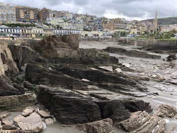 Rock formations on beach against buildings in city