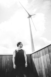 Man standing on wind turbine against sky