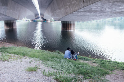 Couple sitting below bridge