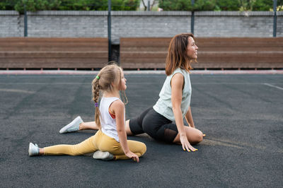 Full length of young woman exercising on road