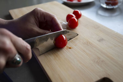 Close up view of someone slicing tomatoes on a cutting board