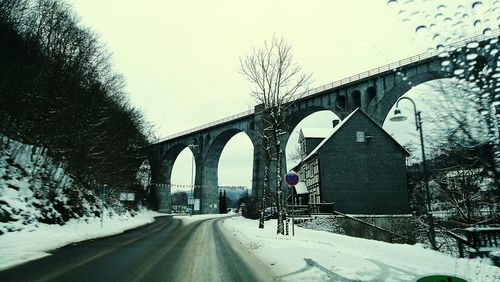 Road by bridge against sky during winter