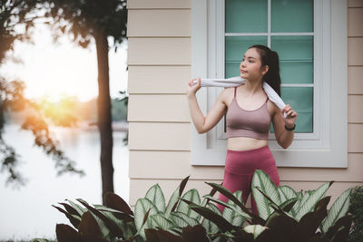 Young woman standing against plants