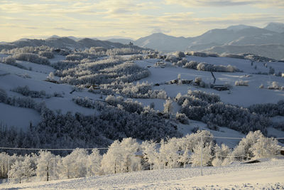 Scenic view of snow covered land and mountains against sky