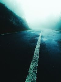 Surface level of road by trees against sky