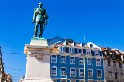 Low angle view of statue against building against clear blue sky