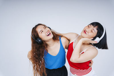 Lesbian couple listening music against gray background