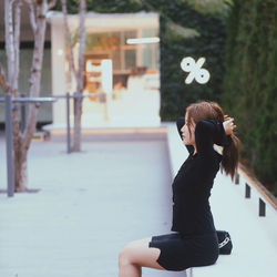 Side view of woman sitting on street