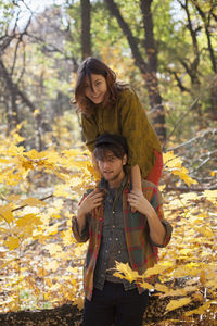 Portrait of a smiling girl standing against trees during autumn