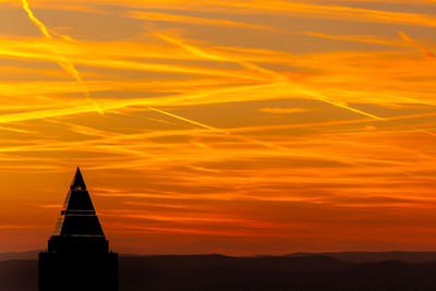 Silhouette building against orange sky during sunset