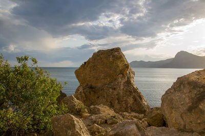 Rocks on shore by sea against sky