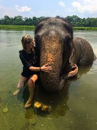 Woman embracing elephant while sitting in river at chitwan national park