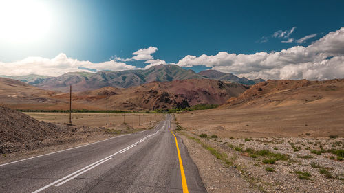 Empty road along landscape and mountains against sky