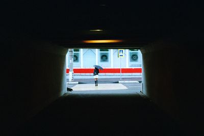 Woman standing in illuminated tunnel