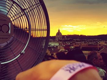 People in city against sky during sunset