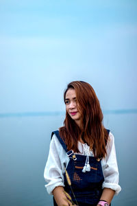 Smiling young woman standing against sky