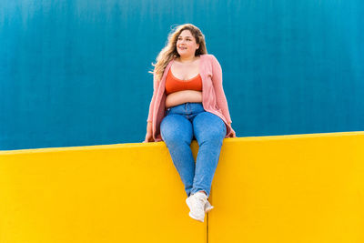 Young woman sitting on wall