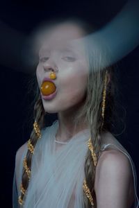 Portrait of woman eating food against black background