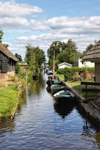 Canal amidst trees and buildings against sky