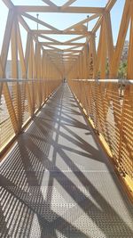Shadow of footbridge on bridge against sky