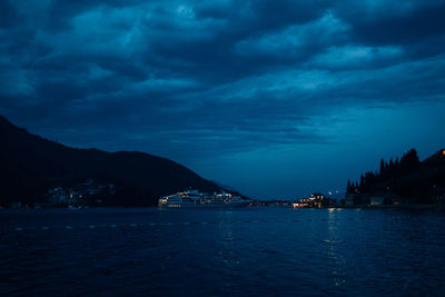 Scenic view of sea by illuminated city against sky