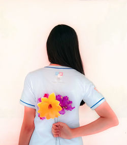 Rear view of woman holding bouquet against white background