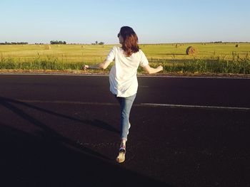 Rear view of woman standing on field against sky