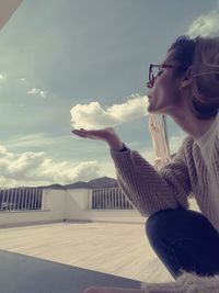 Optical illusion of woman holding clouds during sunny day