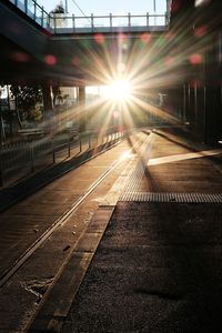 Railroad tracks against bright sun at sunset
