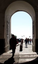 People on archway of building against clear sky