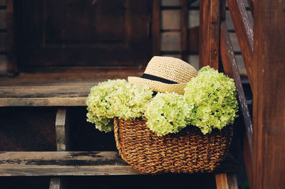 Close-up of flowers with hat in basket on staircase