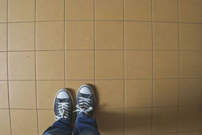 Low section of man standing on tiled floor