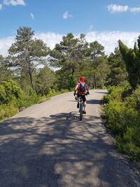 Man riding bicycle on road against sky