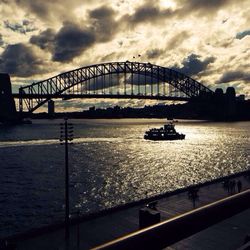 Bridge over river against cloudy sky