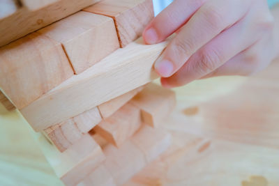 Cropped hand playing wooden block removal game at home