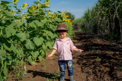 Cute smiling baby boy in hat standing on field