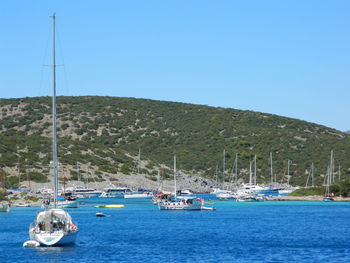 Boats in sea against clear blue sky