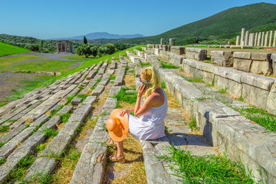 Woman talking on phone while sitting on steps at old ruins
