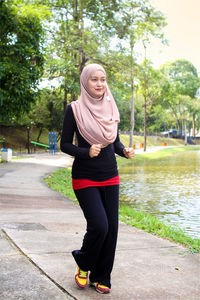 Woman in hijab jogging at park against tree