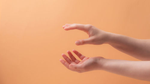 Close-up of woman hand against orange background