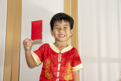 Portrait of smiling girl standing against wall