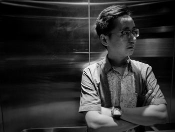 Young man looking away while standing in elevator