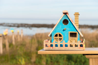 Close-up of wooden birdhouse over field