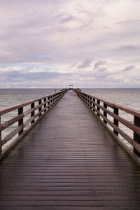 Wooden pier over sea against sky