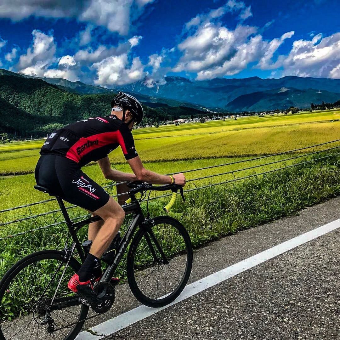 MAN RIDING BICYCLE ON LANDSCAPE AGAINST MOUNTAINS