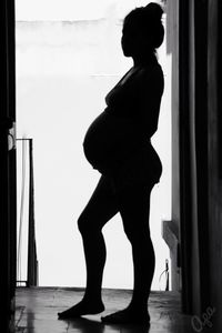 Side view of silhouette woman standing against door at home