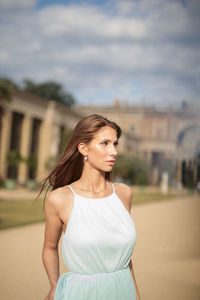 Young woman looking away while standing against building