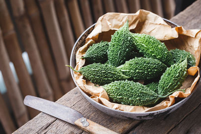 High angle view of bitter gourds in wicker basket on wooden table