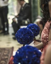 Midsection of bridesmaid holding purple bouquet while sitting in church